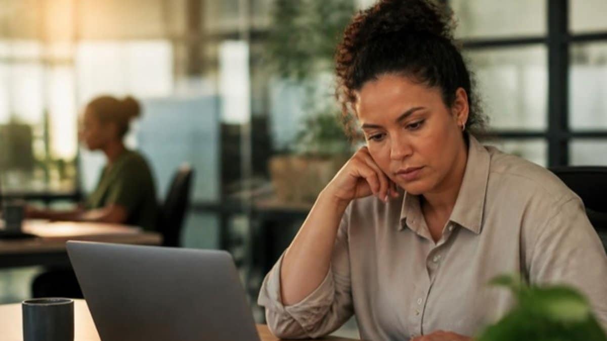 TDAH no trabalho: mulher adulta concentrada entre o notebook e a agenda em um escritório ao fim do dia